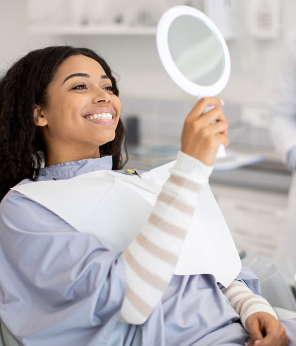 person smiling in mirror at dentist
