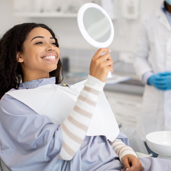 person smiling in mirror at dentist